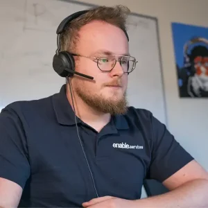 image of man with headset on in a meeting looking at a laptop