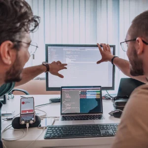 Image of 2 people pointing at a computer screen (developing)